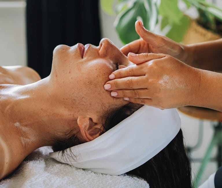 Massage crânien des tempes du visage femme sur dos sur table